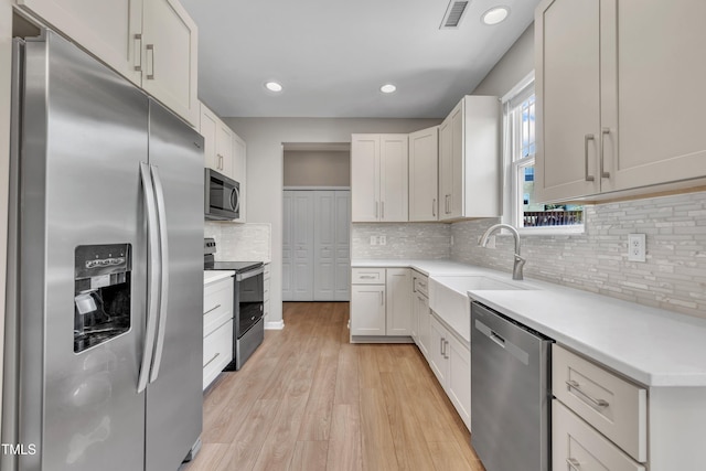 2714 Magnolia Tree Ln, Durham, NC 27703 - kitchen with stainless steel appliances, light wood-style floors, backsplash, light countertops, and recessed lighting