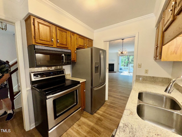 2535 Fairway Dr, Henderson, NC 27536 - kitchen featuring appliances with stainless steel finishes, wood finished floors, ornamental molding, brown cabinetry, and a chandelier