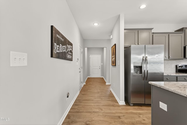 611 Laurel Lake Rd, Salemburg, NC 28385 - kitchen with stainless steel appliances, gray cabinets, backsplash, light stone counters, and light wood-style flooring