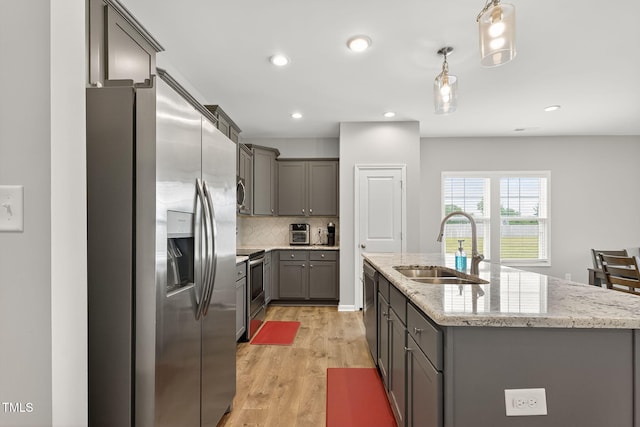 611 Laurel Lake Rd, Salemburg, NC 28385 - kitchen featuring stainless steel appliances, gray cabinetry, an island with sink, decorative backsplash, and light wood finished floors