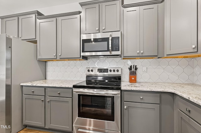 611 Laurel Lake Rd, Salemburg, NC 28385 - kitchen with appliances with stainless steel finishes, gray cabinetry, decorative backsplash, and light stone countertops
