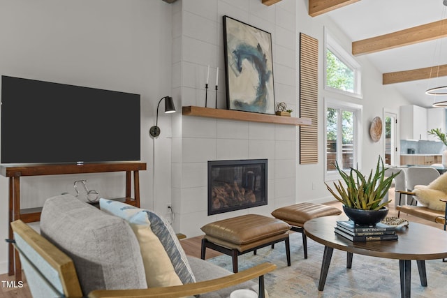 3033 Sylvania Dr, Raleigh, NC 27607 - living room featuring beamed ceiling, wood finished floors, a tiled fireplace, and high vaulted ceiling