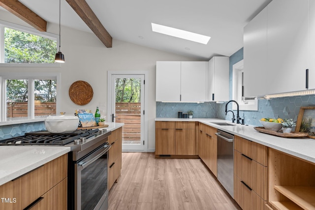 3033 Sylvania Dr, Raleigh, NC 27607 - kitchen featuring appliances with stainless steel finishes, light countertops, a skylight, light wood-type flooring, and backsplash