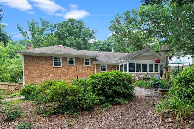 1312 Hampton Valley Rd, Cary, NC 27511 - back of property featuring a chimney, brick siding, roof with shingles, and a sunroom