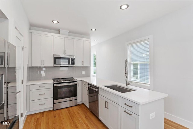 2904 Wadsworth Ave # A, Durham, NC 27707 - kitchen featuring stainless steel appliances, a peninsula, light countertops, backsplash, and light wood finished floors