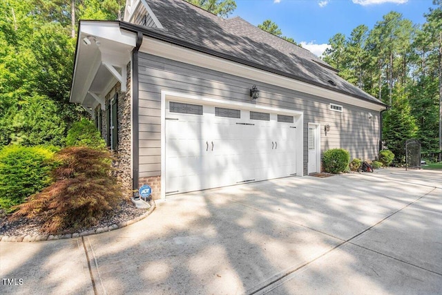 1203 Smith Creek Way, Wake Forest, NC 27587 - view of side of home featuring driveway, a garage, a shingled roof, and stone siding