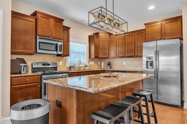 2700 Banks Lake Ct, Fuquay Varina, NC 27526 - kitchen featuring appliances with stainless steel finishes, a breakfast bar area, light stone counters, a center island, and light wood-type flooring