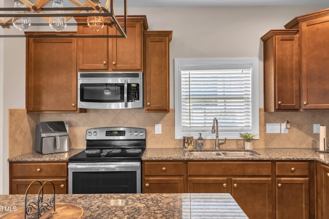 2700 Banks Lake Ct, Fuquay Varina, NC 27526 - kitchen featuring stainless steel appliances, dark stone counters, tasteful backsplash, and brown cabinetry