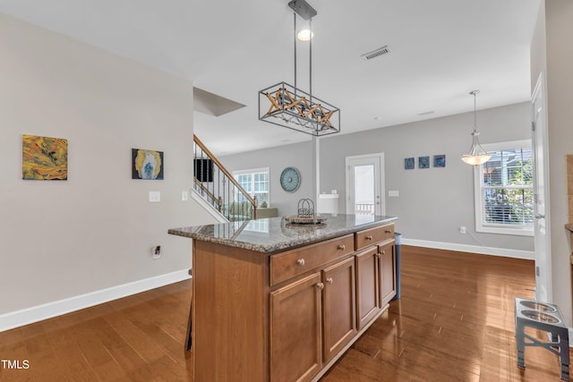 2700 Banks Lake Ct, Fuquay Varina, NC 27526 - kitchen with dark wood-type flooring, a center island, stone counters, pendant lighting, and brown cabinetry