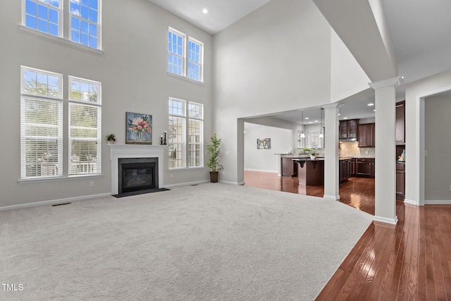 316 Hilliard Forest Dr, Cary, NC 27519 - unfurnished living room featuring decorative columns, a high ceiling, a fireplace with flush hearth, recessed lighting, and dark wood finished floors