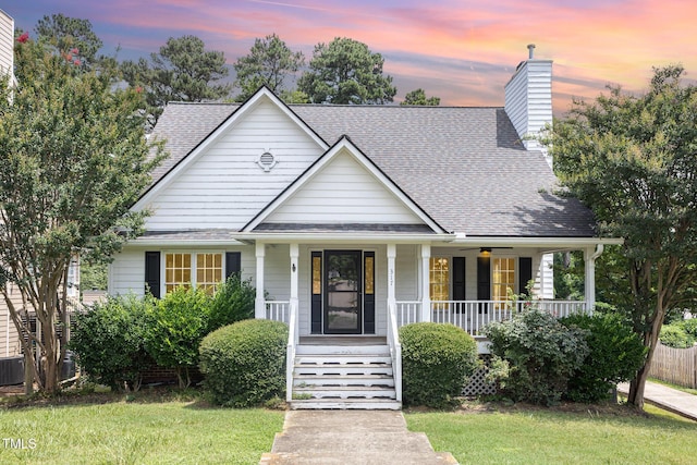 317 Yellow Poplar Ave, Wake Forest, NC 27587 - view of front of house with covered porch, a shingled roof, a front lawn, and a chimney