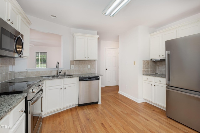 317 Yellow Poplar Ave, Wake Forest, NC 27587 - kitchen with appliances with stainless steel finishes, backsplash, light wood-type flooring, white cabinetry, and light stone counters