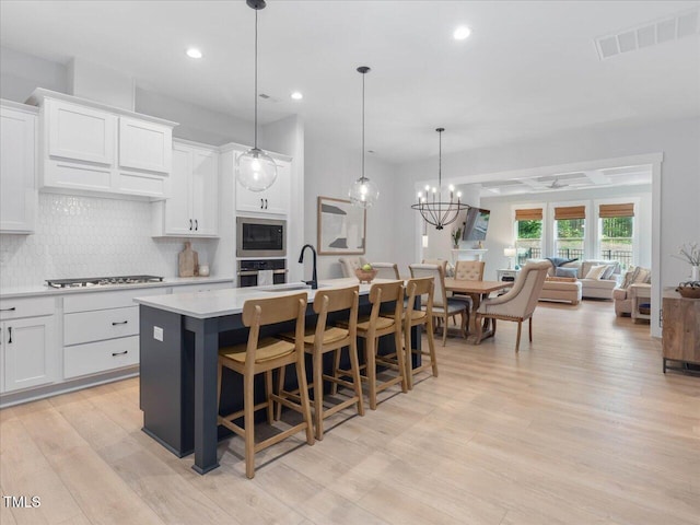 820 Whistable Ave, Wake Forest, NC 27587 - kitchen with stainless steel appliances, an island with sink, tasteful backsplash, light wood finished floors, and light countertops