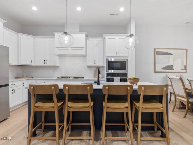 820 Whistable Ave, Wake Forest, NC 27587 - kitchen featuring appliances with stainless steel finishes, tasteful backsplash, light countertops, a kitchen island with sink, and recessed lighting