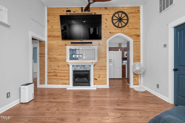 196 Red Wing Dr, Louisburg, NC 27549 - unfurnished living room featuring wood finished floors, a fireplace with raised hearth, wooden walls, and arched walkways