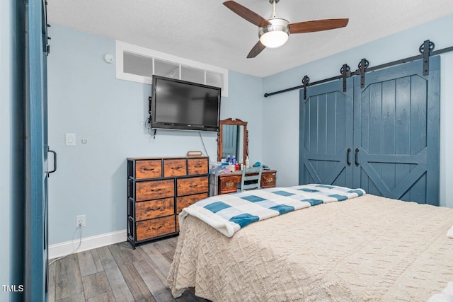196 Red Wing Dr, Louisburg, NC 27549 - bedroom with a barn door, wood finished floors, a ceiling fan, and a textured ceiling