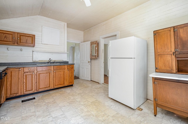 805 N Duke St, Durham, NC 27701 - kitchen featuring freestanding refrigerator, wooden walls, vaulted ceiling, brown cabinets, and light flooring