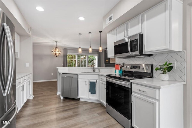 7771 Falcon Rest Cir, Raleigh, NC 27615 - kitchen with stainless steel appliances, a peninsula, white cabinetry, a chandelier, and recessed lighting