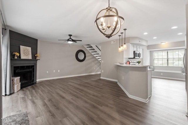 7771 Falcon Rest Cir, Raleigh, NC 27615 - unfurnished living room featuring stairway, a chandelier, recessed lighting, dark wood-style floors, and a fireplace