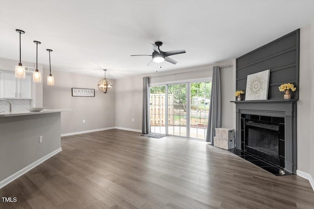 7771 Falcon Rest Cir, Raleigh, NC 27615 - unfurnished living room featuring a ceiling fan, a tiled fireplace, wood finished floors, and a chandelier