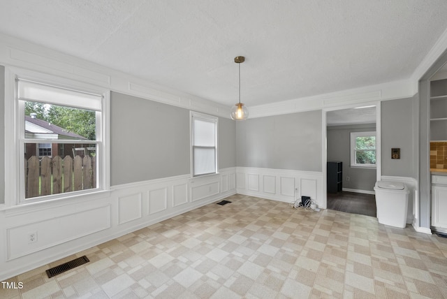 2510 Springhill Ave, Raleigh, NC 27603 - unfurnished dining area with a textured ceiling, a decorative wall, and wainscoting