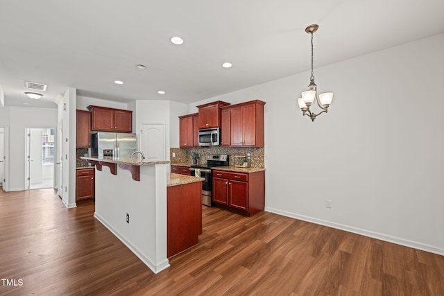 120 Holly Berry Ln, Durham, NC 27703 - kitchen featuring stainless steel appliances, decorative backsplash, a kitchen bar, dark wood finished floors, and recessed lighting