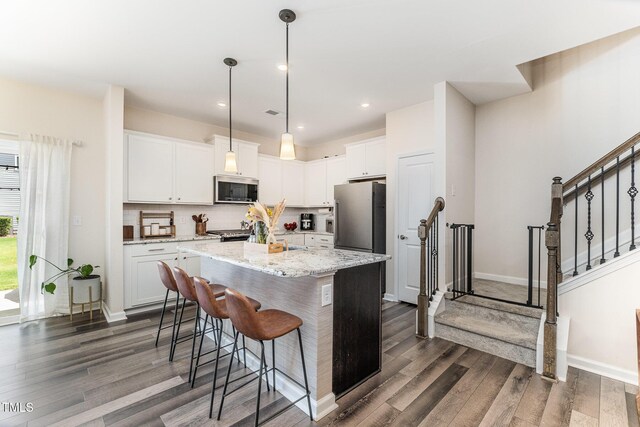 3019 Newfields Pl, Durham, NC 27703 - kitchen with appliances with stainless steel finishes, dark wood finished floors, backsplash, a breakfast bar, and recessed lighting