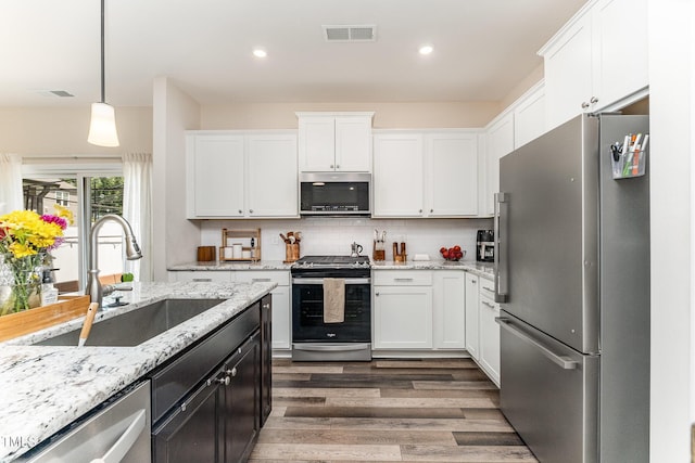 3019 Newfields Pl, Durham, NC 27703 - kitchen with appliances with stainless steel finishes, wood finished floors, white cabinets, pendant lighting, and recessed lighting