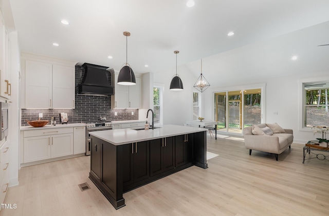 3714 Ode Turner Rd, Hillsborough, NC 27278 - kitchen featuring wall chimney exhaust hood, stainless steel range, decorative backsplash, light countertops, and light wood-style floors