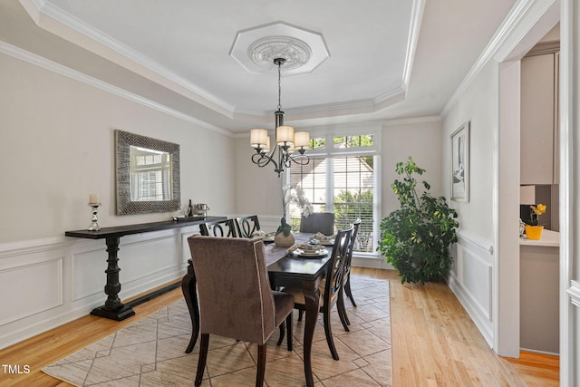 100 Beraneak Ln, Cary, NC 27519 - dining room featuring a tray ceiling, a chandelier, light wood-style floors, crown molding, and a decorative wall