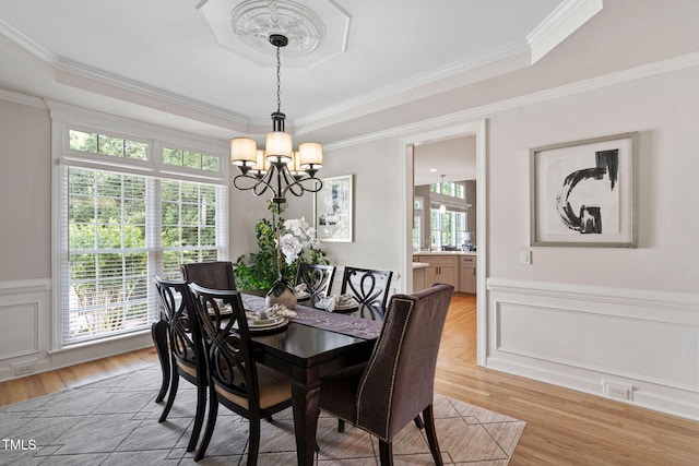 100 Beraneak Ln, Cary, NC 27519 - dining area featuring a chandelier, a raised ceiling, light wood-style flooring, a wainscoted wall, and ornamental molding