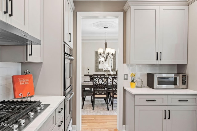 100 Beraneak Ln, Cary, NC 27519 - kitchen with appliances with stainless steel finishes, a chandelier, backsplash, crown molding, and ventilation hood