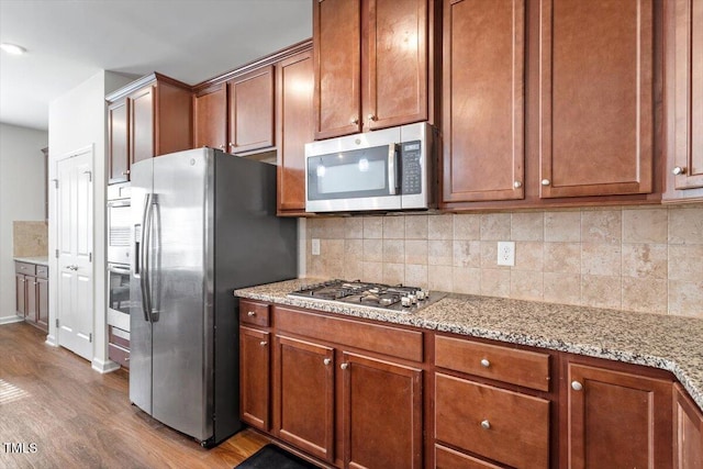 1035 Brownsmith Dr, Apex, NC 27502 - kitchen with appliances with stainless steel finishes, wood finished floors, decorative backsplash, and light stone counters