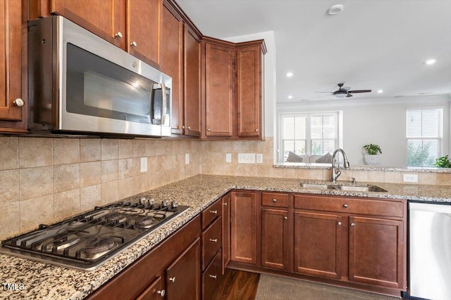 1035 Brownsmith Dr, Apex, NC 27502 - kitchen with appliances with stainless steel finishes, a ceiling fan, light stone countertops, tasteful backsplash, and ornamental molding