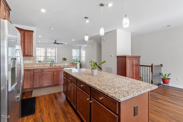 1035 Brownsmith Dr, Apex, NC 27502 - kitchen with stainless steel fridge with ice dispenser, dark wood-style flooring, a kitchen island, a ceiling fan, and light stone countertops