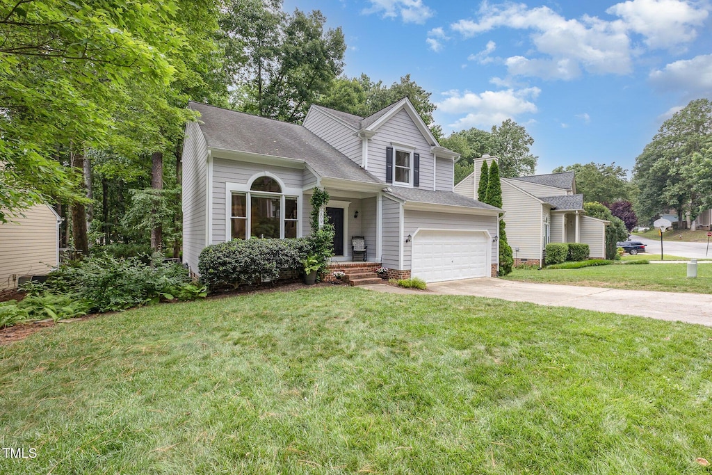 8209 Greywinds Dr, Raleigh, NC 27615 - traditional-style home with concrete driveway, a garage, a front lawn, and roof with shingles