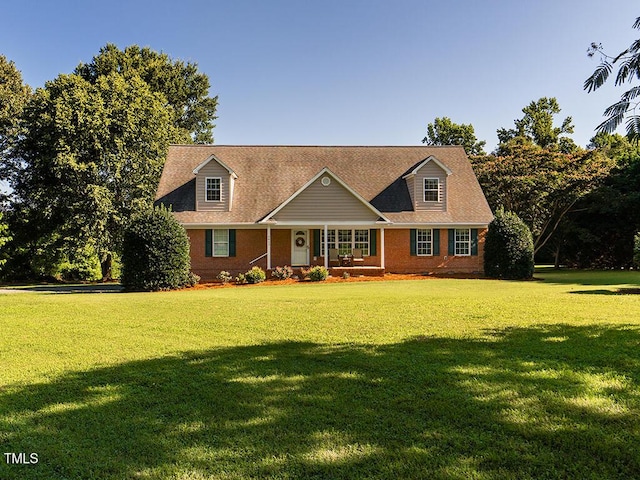 6843 Sawyer Rd, Liberty, NC 27298 - cape cod house featuring covered porch, a front yard, and brick siding