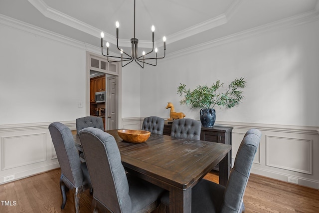 6104 Spicewood Dr, Fuquay Varina, NC 27526 - dining area with a chandelier, wood finished floors, a decorative wall, a tray ceiling, and crown molding