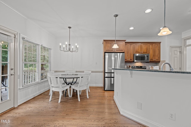6104 Spicewood Dr, Fuquay Varina, NC 27526 - kitchen with stainless steel appliances, brown cabinetry, ornamental molding, a chandelier, and pendant lighting