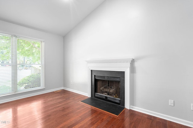 2912 Enson Pl, Raleigh, NC 27603 - unfurnished living room with vaulted ceiling, wood finished floors, and a fireplace with flush hearth