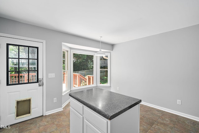 2912 Enson Pl, Raleigh, NC 27603 - kitchen with dark countertops, white cabinetry, stone tile floors, a center island, and pendant lighting