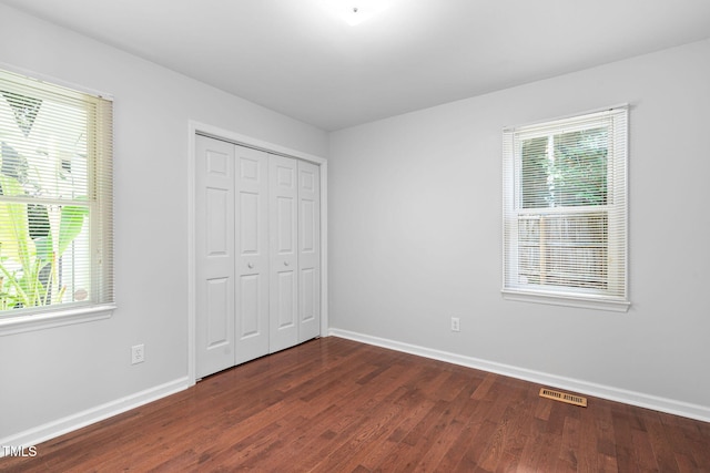 2912 Enson Pl, Raleigh, NC 27603 - unfurnished bedroom featuring dark wood-style flooring, multiple windows, and a closet