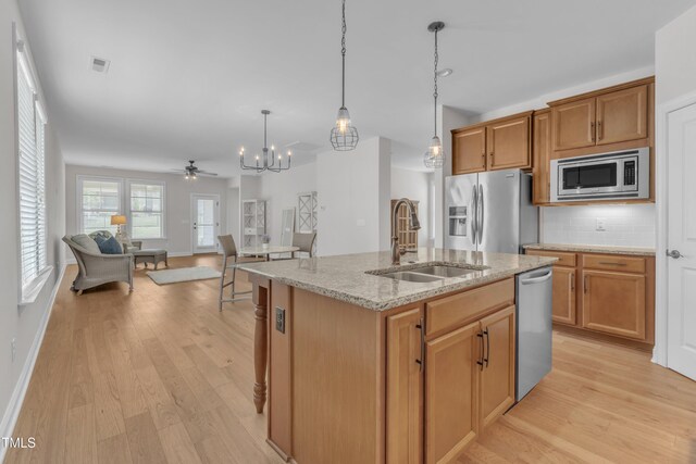 1003 Branwell Dr, Durham, NC 27703 - kitchen featuring appliances with stainless steel finishes, light wood-style floors, a chandelier, decorative backsplash, and light stone countertops
