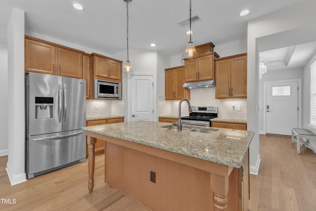 1003 Branwell Dr, Durham, NC 27703 - kitchen with appliances with stainless steel finishes, light wood finished floors, under cabinet range hood, brown cabinetry, and recessed lighting