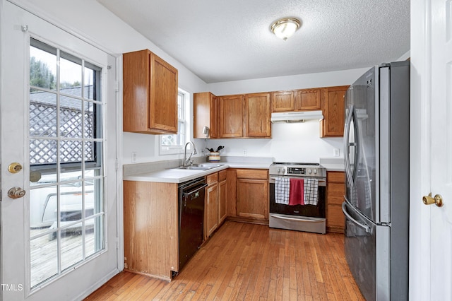 405 E Maple Ave, Holly Springs, NC 27540 - kitchen with stainless steel appliances, under cabinet range hood, light wood finished floors, light countertops, and brown cabinetry