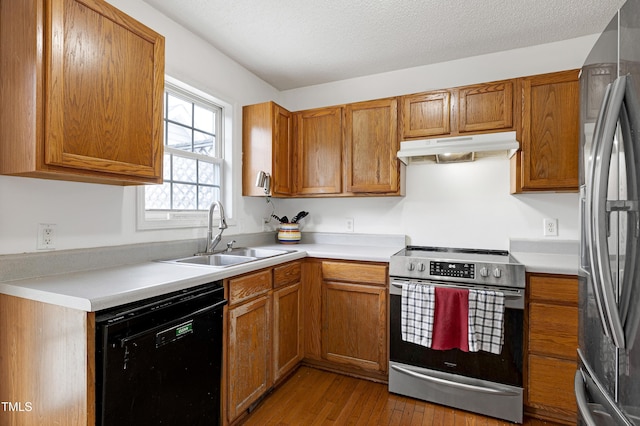 405 E Maple Ave, Holly Springs, NC 27540 - kitchen with appliances with stainless steel finishes, under cabinet range hood, wood finished floors, and brown cabinets