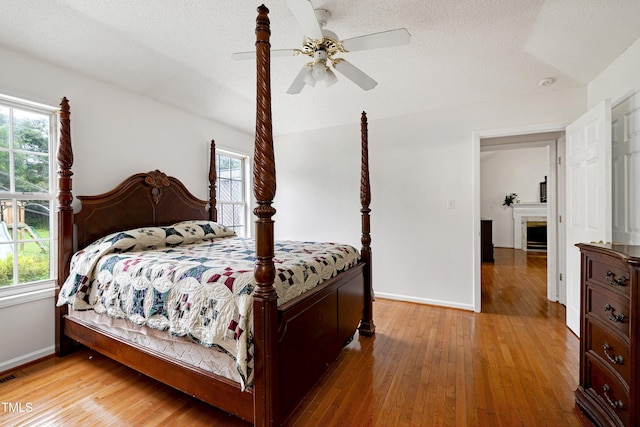 405 E Maple Ave, Holly Springs, NC 27540 - bedroom with wood finished floors, a ceiling fan, a fireplace, and a textured ceiling
