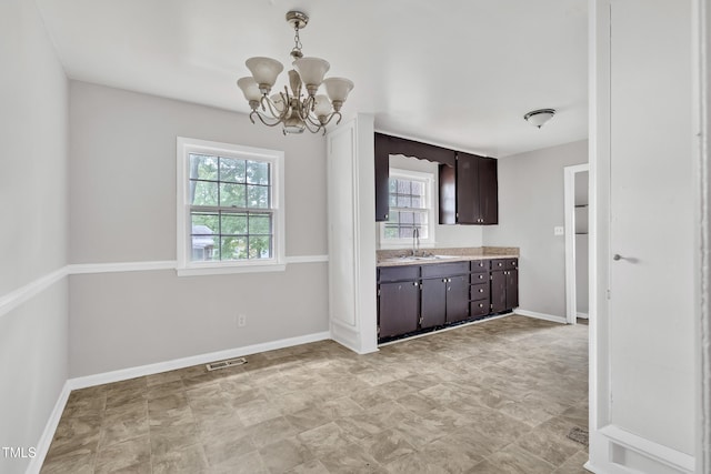 1220 Blarney Ct, Raleigh, NC 27610 - kitchen with plenty of natural light, light countertops, dark brown cabinetry, and a chandelier