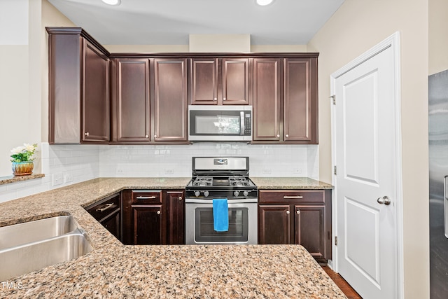 677 Wickham Ridge Rd, Apex, NC 27539 - kitchen with stainless steel appliances, light stone counters, dark brown cabinetry, and tasteful backsplash