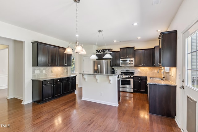 4 Seawell Ct, Durham, NC 27703 - kitchen featuring appliances with stainless steel finishes, light stone counters, a kitchen breakfast bar, tasteful backsplash, and dark wood-style floors